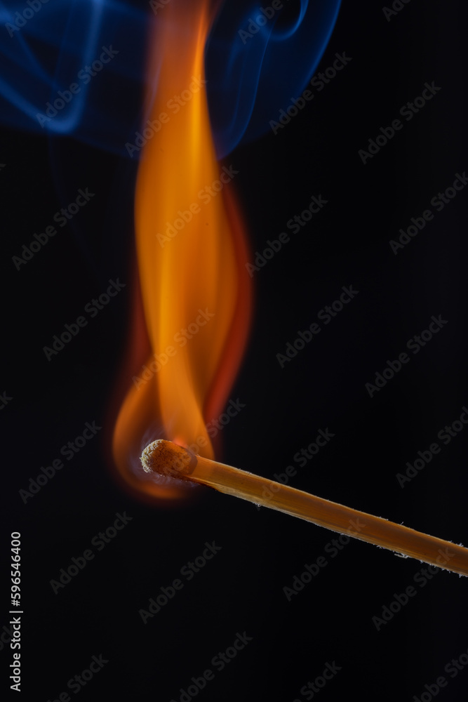 A glowing red match burns on a dark background, surrounded by fine wisps of smoke. Heat and flames create a flickering orange light, briefly illuminating the room. A glowing red match burns on a dark background, surrounded by fine wisps of smoke. Heat and flames create a flickering orange light, briefly illuminating the room.