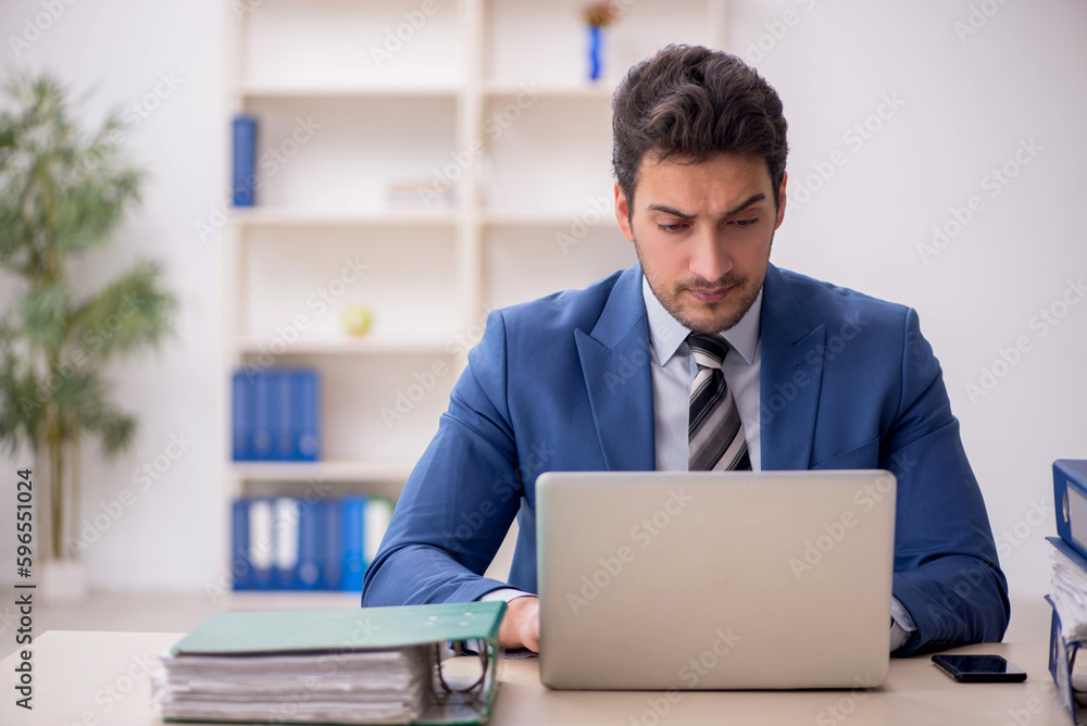 Young male employee and too much work in the office Young male employee and too much work in the office