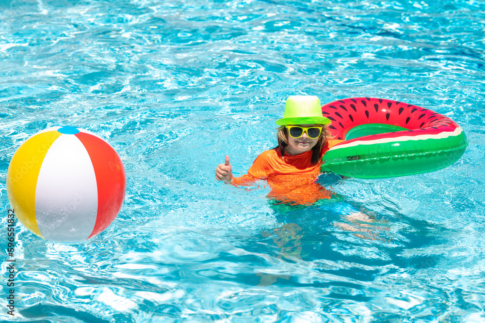 Happy kid playing with colorful swim ring in swimming pool on summer day. Child water vacation. Children play in tropical resort. Child swim in summer pool water.