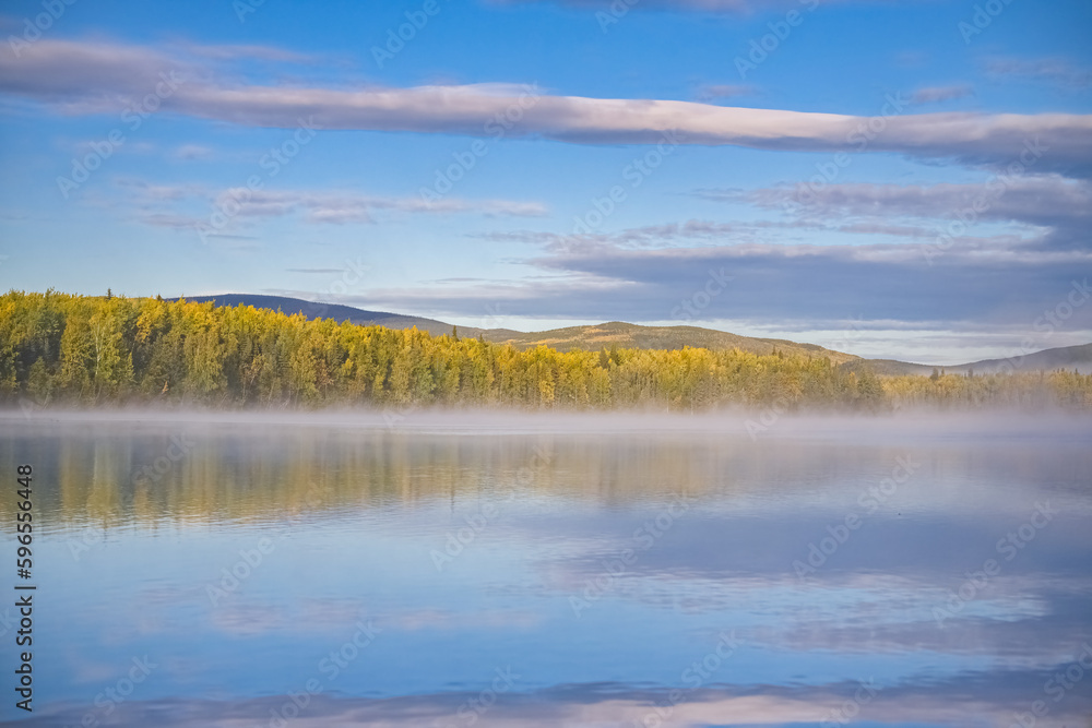 Yukon in Canada, wild landscape in autumn of the Tombstone park, reflection of the trees in a lake at sunrise
