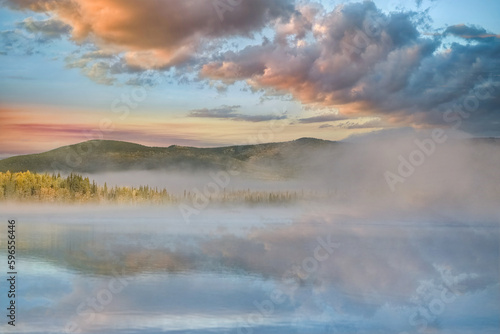 Yukon in Canada, wild landscape in autumn of the Tombstone park, reflection of the trees in a lake at sunrise 