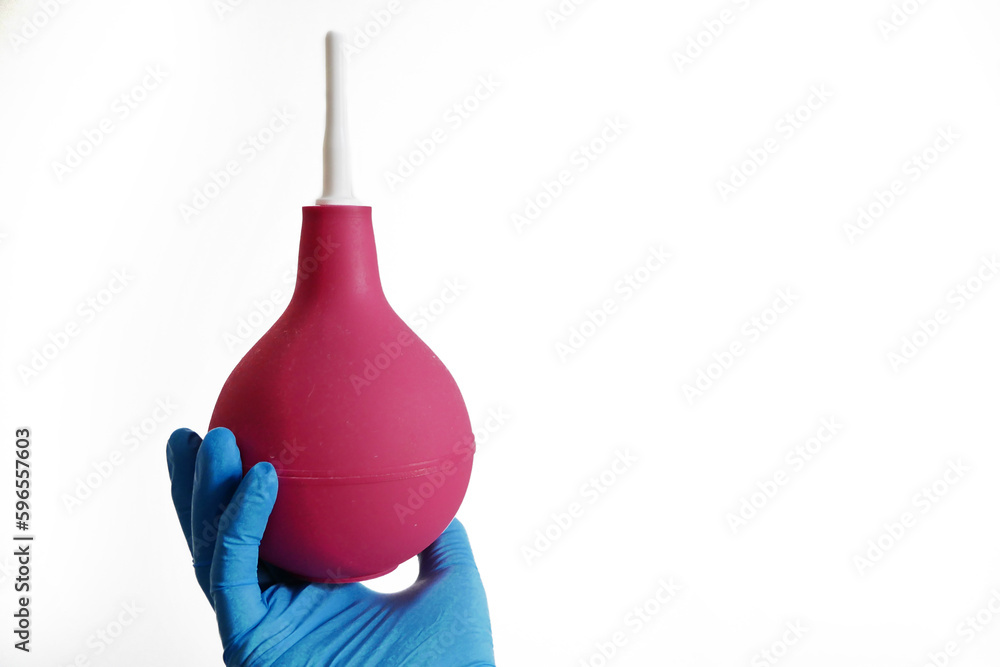 Doctor in blue medical gloves holding red enema isolated on white background, concept Doctor in blue medical gloves holding red enema isolated on white background, concept