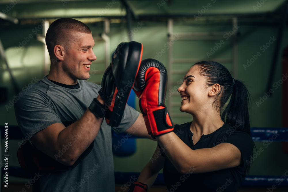 A boxing coach is giving high five to a girl fighter after a successful training