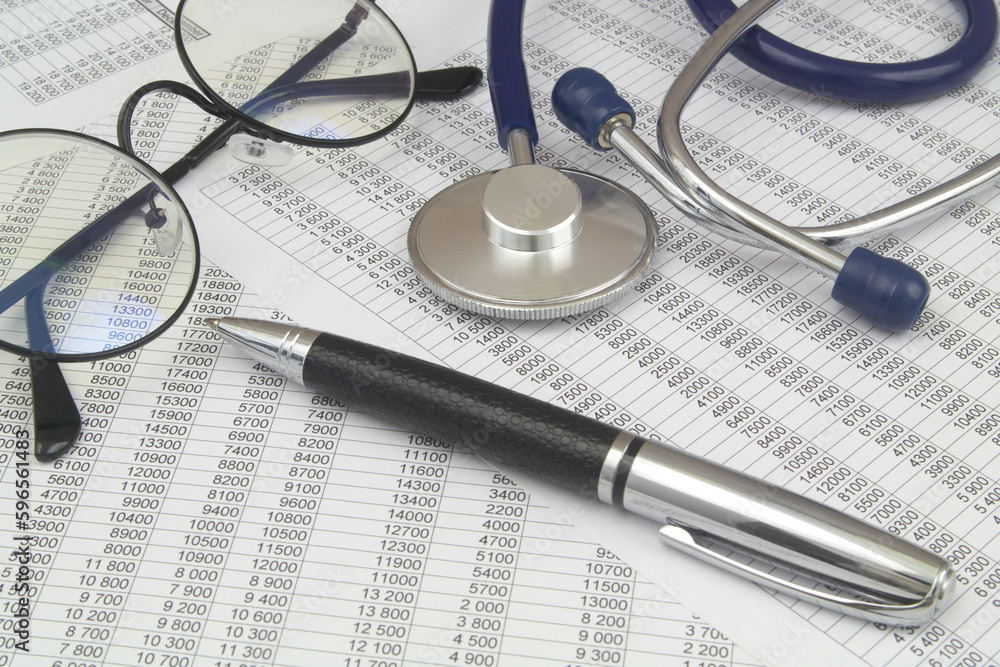 Documents with numbers, eyeglasses and stethoscope with pen close up. Documents with numbers, eyeglasses and stethoscope with pen close up.