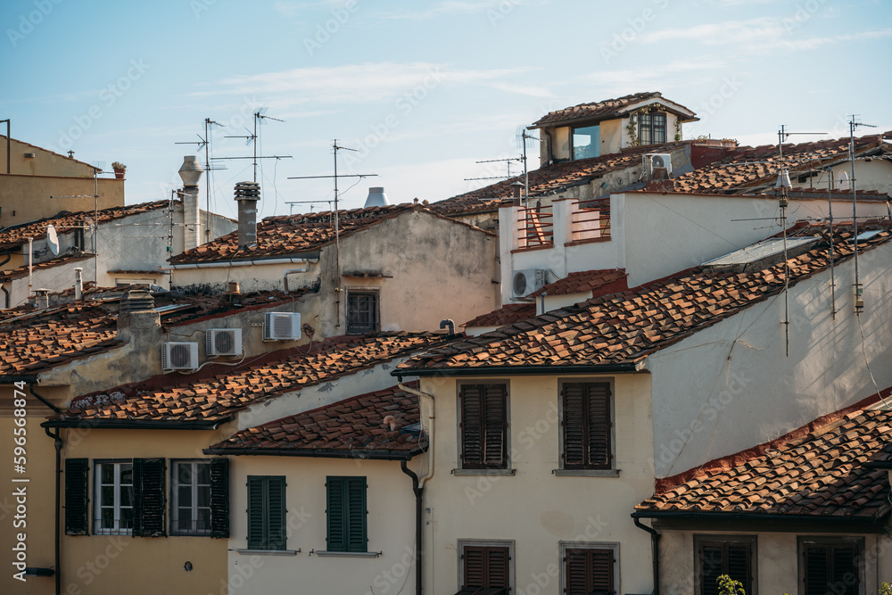 The tiled roofs of old houses are illuminated by sunlight on a warm summer day in Italy. The concept of ancient buildings and city attractions
