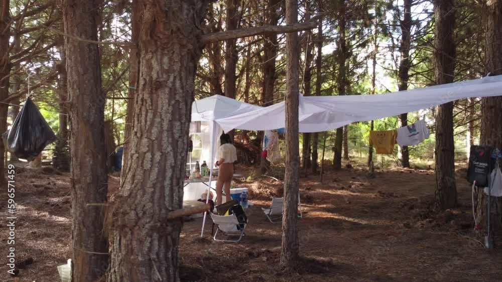 A young woman prepares breakfast in the tent camp in a pine forest. Panning shot