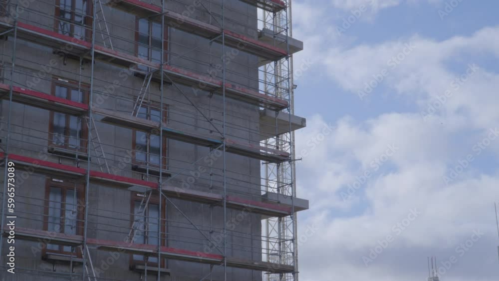 Scaffolding set up next to a building under construction - modern construction - zoom out Scaffolding set up next to a building under construction - modern construction - zoom out