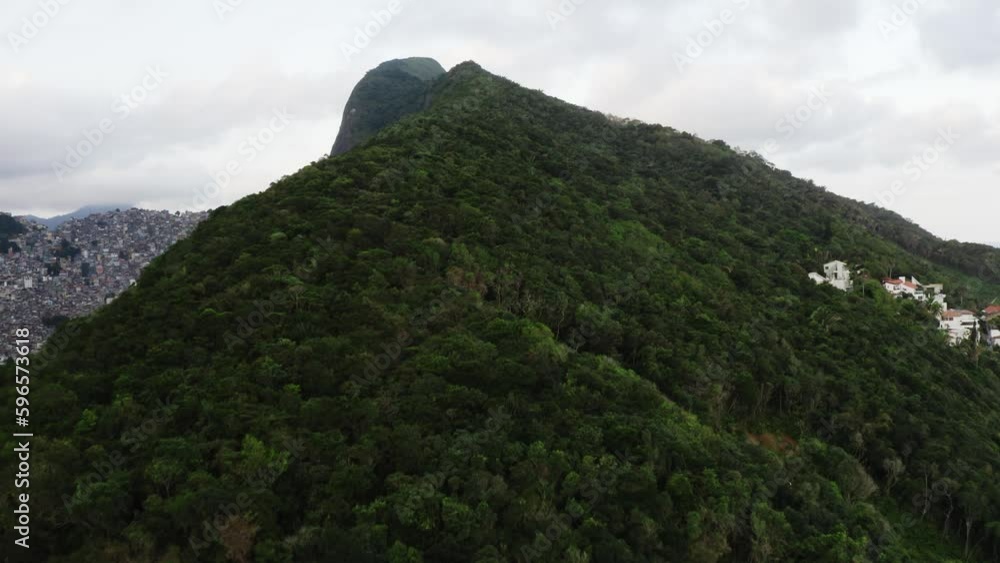 Ascending drone flight over greened mountain and Favela Neighborhood in Background - Rio de Janeiro, Brazil Ascending drone flight over greened mountain and Favela Neighborhood in Background - Rio de Janeiro, Brazil