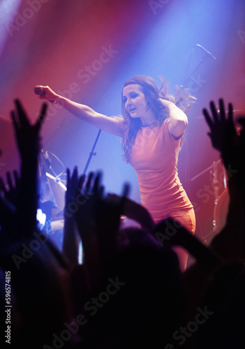People hands, singer woman and concert at night performance, singing and gen z in lights, celebration or cheers. Musician person on stage and microphone at event with fans, crowd or audience dancing