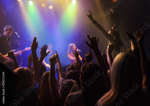 Stage, lights and fans at rock concert or music festival, neon light and energy at live event. Dance, fun and purple lighting, group of excited people in arena at band performance or crowd at party.