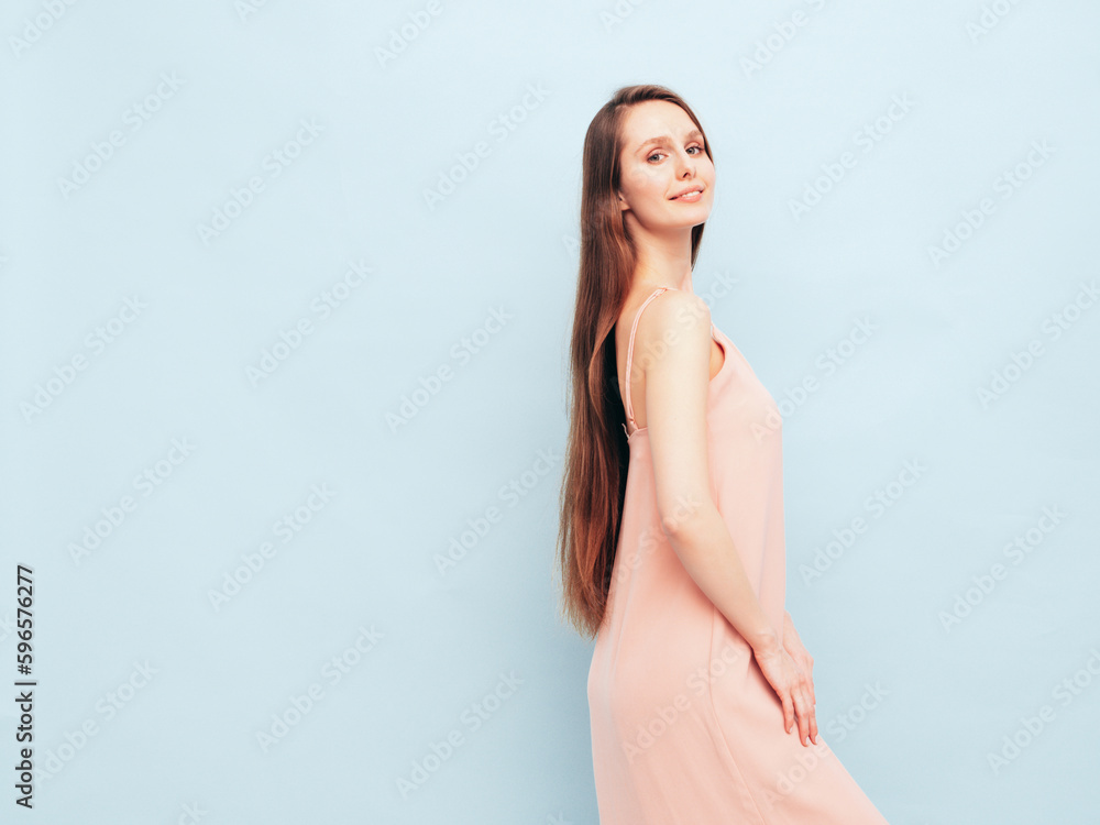 Portrait of young winsome woman in romantic attire pretty smiling on blue background. Slim female in pure pink dress posing in studio. Cheerful model. Isolated. Long hair Portrait of young winsome woman in romantic attire pretty smiling on blue background. Slim female in pure pink dress posing in studio. Cheerful model. Isolated. Long hair