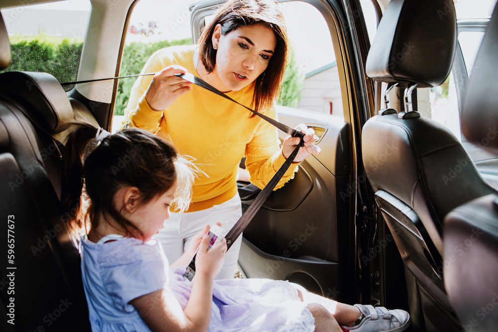 latin mother put her daughter in a car seat and fastens her seat belts for  protection during the trip in the car in Mexico, hispanic family Stock  Photo | Adobe Stock