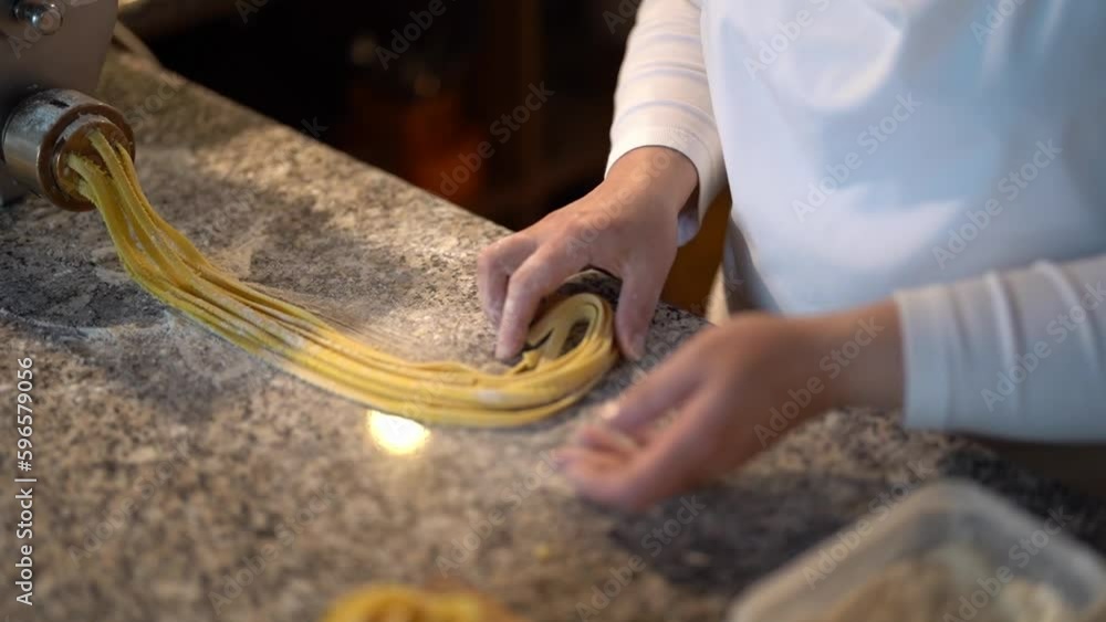 Above angle of anonymous female chef making spaghetti noodles using