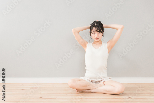 家でストレッチ・柔軟体操をするアジア人女性（脱毛・ヨガ） 
