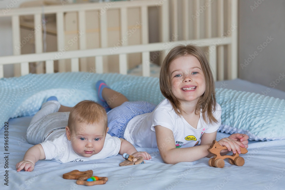 Family, childhood and love. A little girl in bed in a bright bedroom playing with her younger newborn brother. Children, motherhood. Family, childhood and love. A little girl in bed in a bright bedroom playing with her younger newborn brother. Children, motherhood.