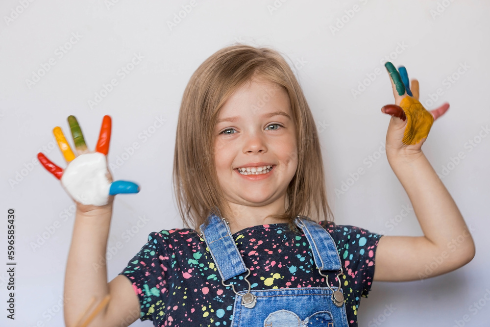 A happy little girl of 4 years draws. The child's hands are covered with paint. The focus of the camera is on the palms. Children's games for child development. Kindergarten. A happy little girl of 4 years draws. The child's hands are covered with paint. The focus of the camera is on the palms. Children's games for child development. Kindergarten.
