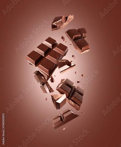 Broken bar of dark chocolate in the air on a brown background