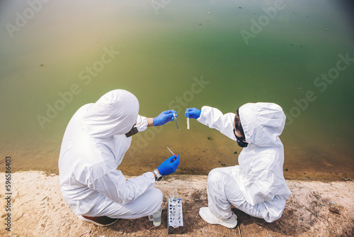Scientists with protective suit holding a test tube with sample water in their hands. Water pollution examine concept