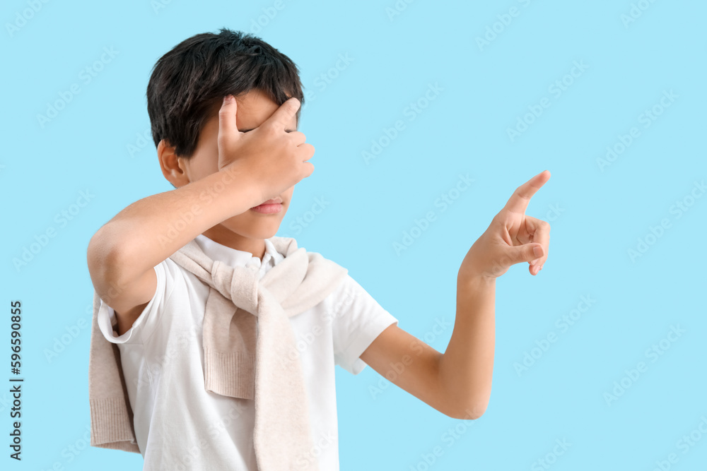 Little boy closing eyes while using virtual screen on blue background Little boy closing eyes while using virtual screen on blue background