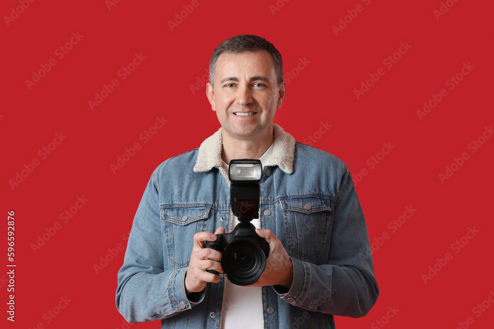 Mature photographer with professional camera on red background Mature photographer with professional camera on red background