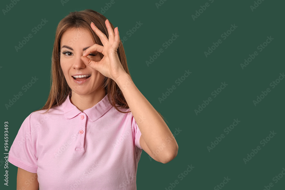 Beautiful woman in pink t-shirt showing OK on green background Beautiful woman in pink t-shirt showing OK on green background