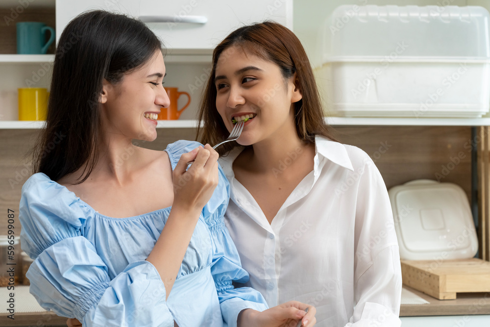 Young beautiful LGBT woman and girlfriend eating breakfast in kitchen Young beautiful LGBT woman and girlfriend eating breakfast in kitchen