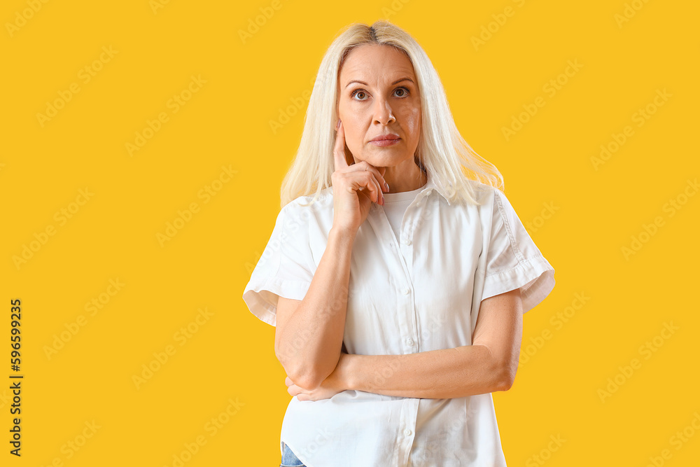 Thoughtful mature woman on yellow background Thoughtful mature woman on yellow background