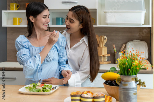 Young beautiful LGBT woman and girlfriend eating breakfast in kitchen