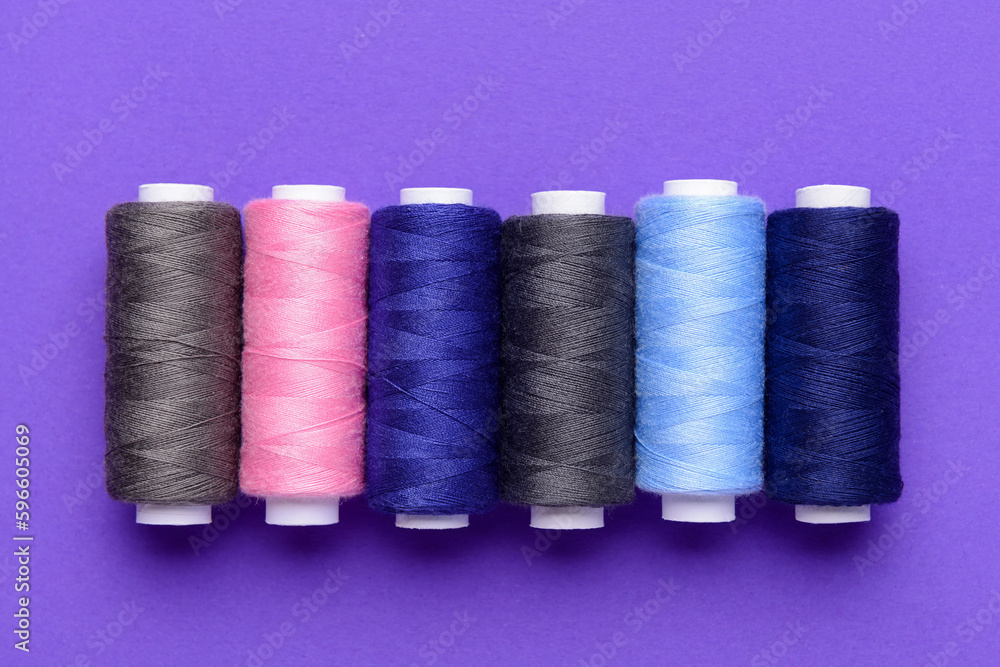 Set of different thread spools on purple background Set of different thread spools on purple background