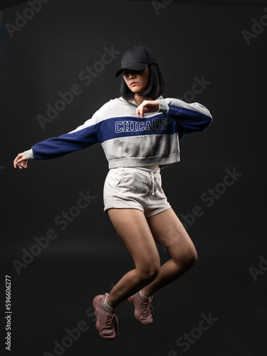 A portrait of a casual fashion-style Asian (Chinese Indonesian) Girl posing dan dancing with a Hip hop style. Isolated on a black background © Daniel