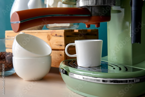 Modern coffee machine and cups on table, closeup