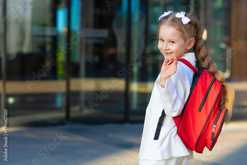 Happy little girl pupil schoolgirl student with backpack schoolbag outdoor. kid back to school. Child education. copy space, text