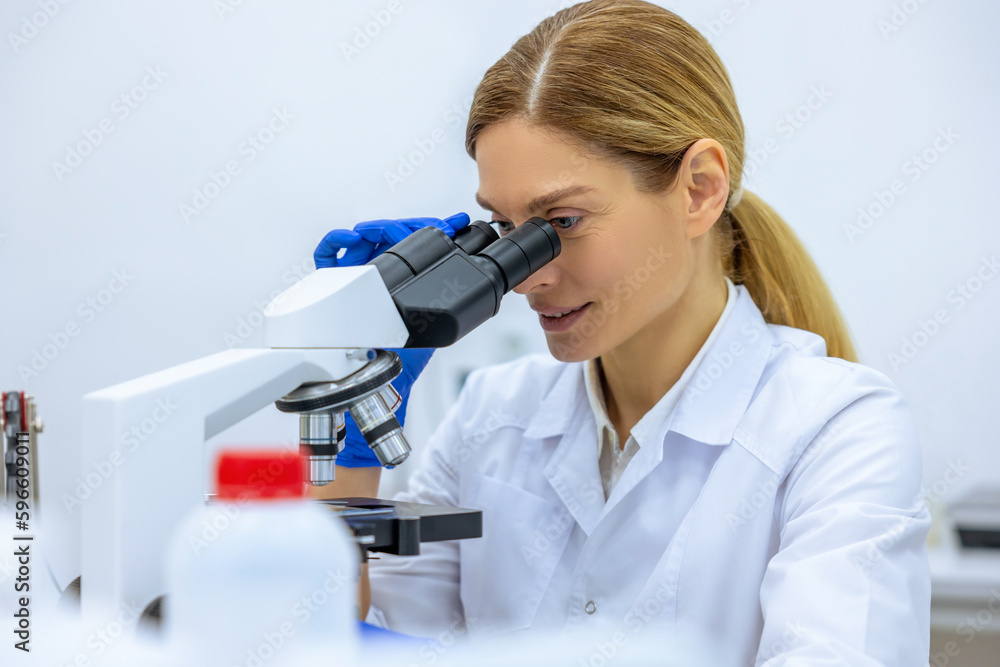 Scientist looking under microscope, doing analysis of test sample ambitious biotechnology specialist Scientist looking under microscope, doing analysis of test sample ambitious biotechnology specialist