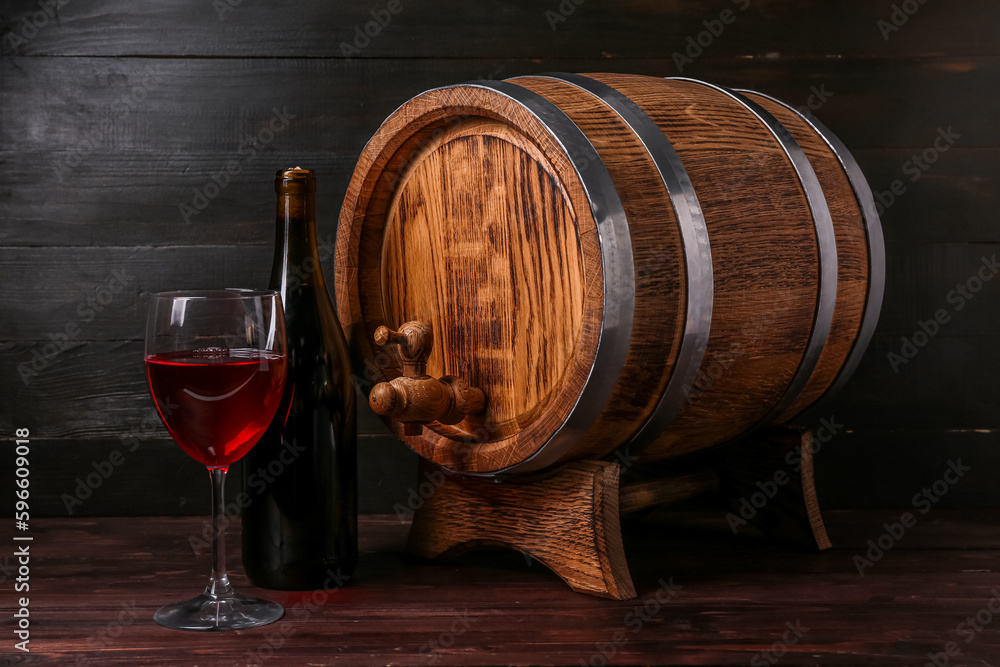 Oak barrel with bottle and glass of wine on dark wooden background ...