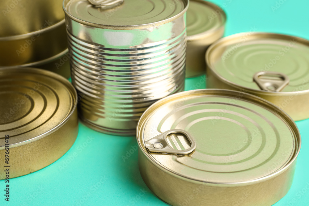 Tin cans with fish on turquoise background, closeup Tin cans with fish on turquoise background, closeup