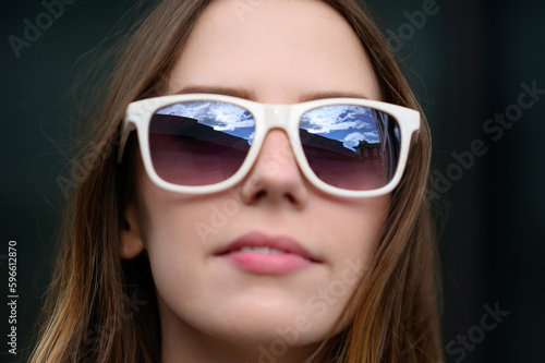 Young happy woman in summer clothes, sunglasses posing against the backdrop of a business center, taking a selfie portrait, close-up.Summer, technology concept