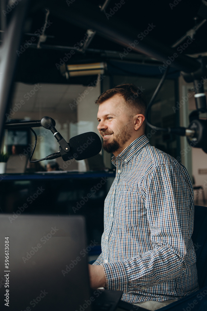 Handsome happy young male radio host broadcasting in studio, using microphone and headphones. Handsome happy young male radio host broadcasting in studio, using microphone and headphones.