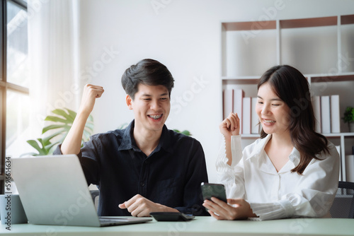 Asian couple looking laptop with happy together in the home. Success of lovers in front of a notebook. Happy couple on social online with a laptop.