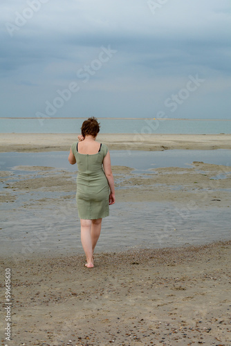 Young woman in dress is standing in front of the sea