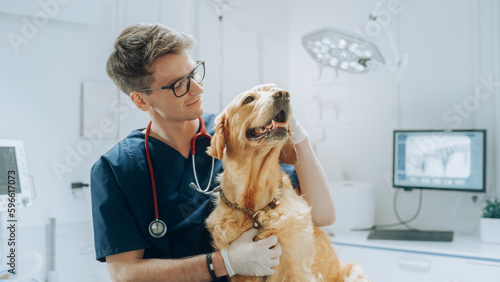 Portrait of a Young Veterinarian in Glasses Petting a Noble Healthy Golden Retriever Pet in a Modern Veterinary Clinic. Handsome Man Looking at Camera and Smiling Together with the Dog. Static Footage photo