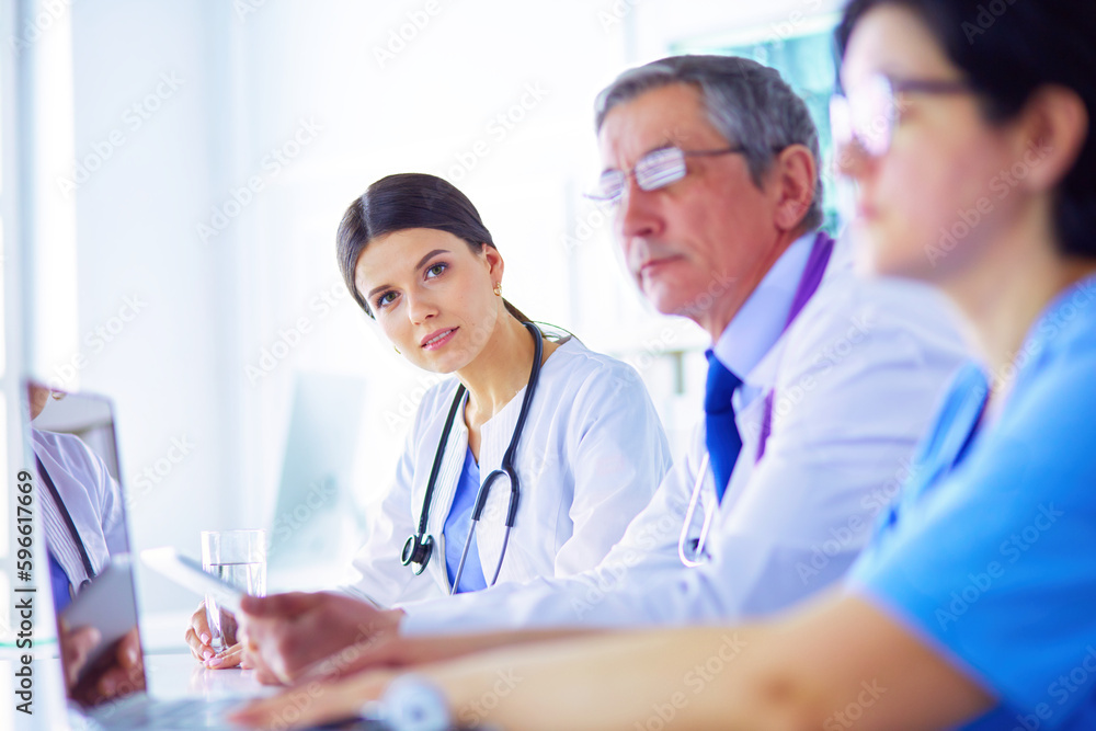Serious medical team using a laptop in a bright office Serious medical team using a laptop in a bright office