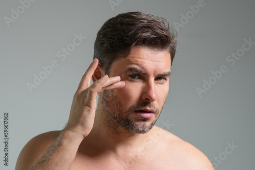 Close-up portrait of perfect brunet man touching chin and skin. Handsome man touching face in gray studio isolated background. Perfect skin. Man cosmetic, skin treatment. Hygiene skin care male face.