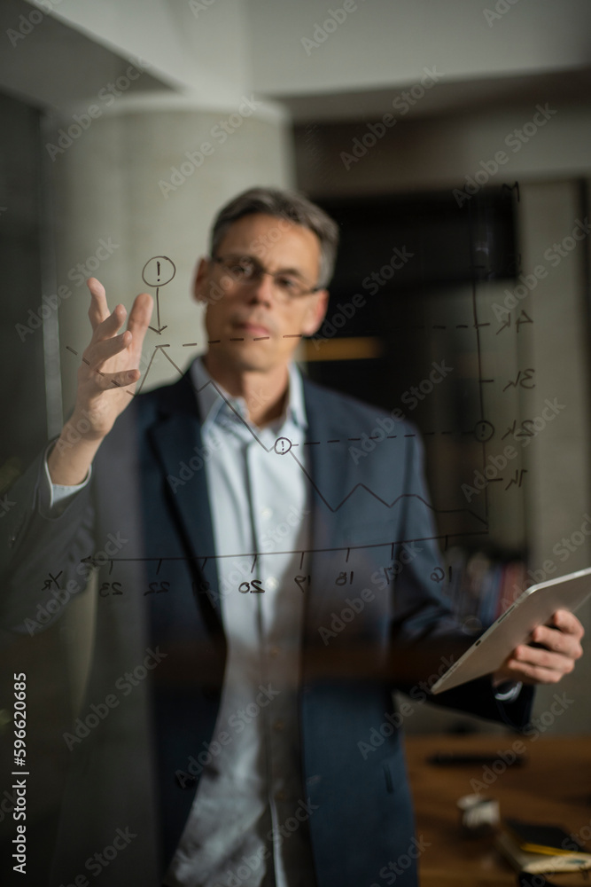Portrait of successful businessman in office. Man writing on the glass board in office Portrait of successful businessman in office. Man writing on the glass board in office