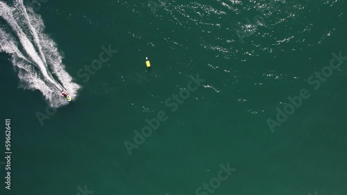 Top down aerial drone view of fast jetskier making a curve leaving a wake on the water, captured in Vilamoura, Algarve, Portugal photo