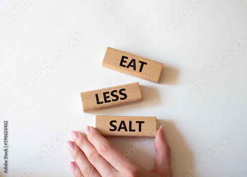 Eat less salt symbol. Concept word Eat less salt on wooden blocks. Businessman hand. Beautiful white background. Business and Eat less salt concept. Copy space