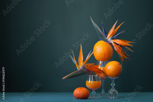 exotic still life with bird of paradise flowers, orange juice and orange fruits photo