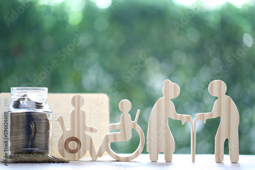 Mutual fund,Love couple senior and wheelchair user with stack of coins money in glass bottle on natural green background, Save money for handicapped person and pension retirement concept