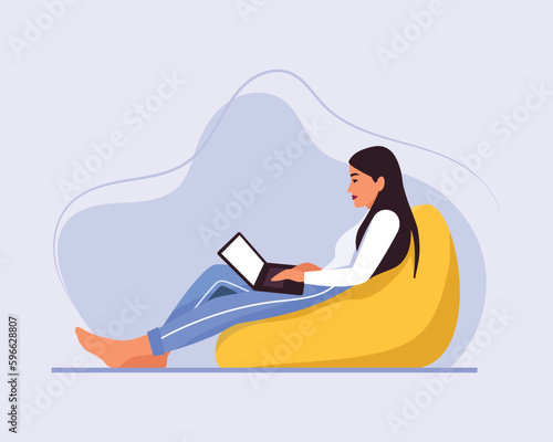 light-skinned girl with long hair sits on a bean bag chair with a laptop