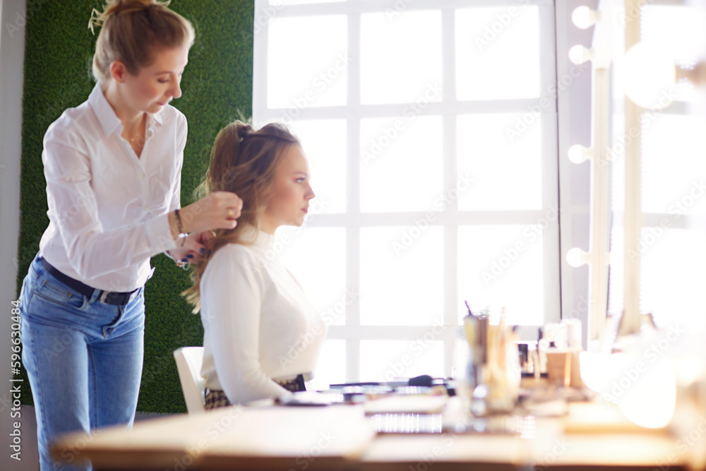Fototapeta premium Happy young woman and hairdresser with fan making hot styling at hair salon.