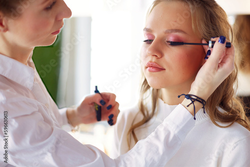 make up artist doing professional make up of young woman.